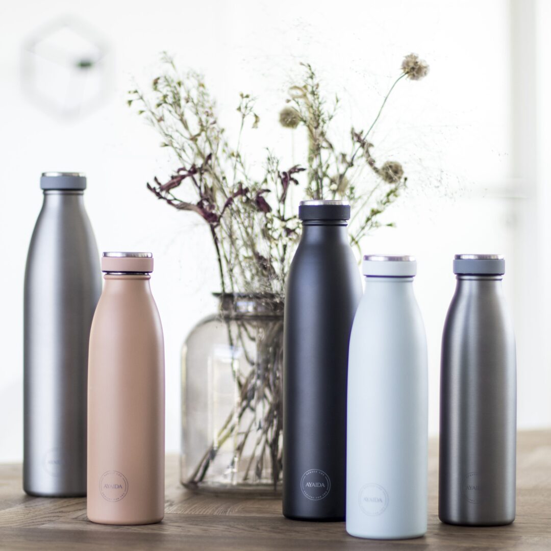 Drikkeflasker fra AYA&IDA ved en vase med tørrede blomster